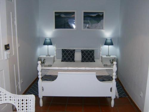 ナザレにあるCasas Da Roseira 2+1 Famalicao Nazareのランプ2つ付きの部屋の白いベッド1台