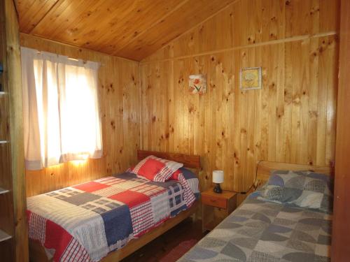 1 dormitorio con 2 camas en una cabaña de madera en Cabañas Antilhue, en Olmué