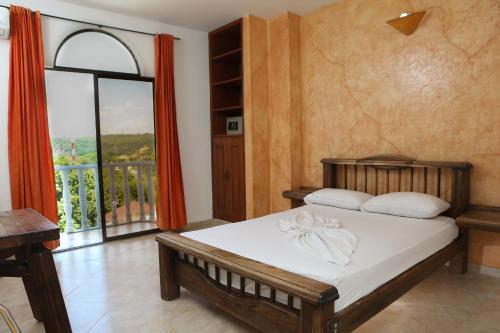 a bedroom with a bed and a large window at Hotel Anamichu Suites in Melgar