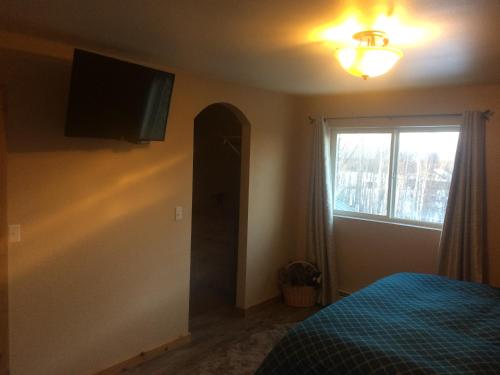 a bedroom with a bed and a television on the wall at Fishhook Sunrise B&B in Palmer