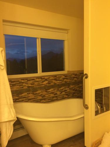 a bathroom with a bath tub and a window at Fishhook Sunrise B&B in Palmer