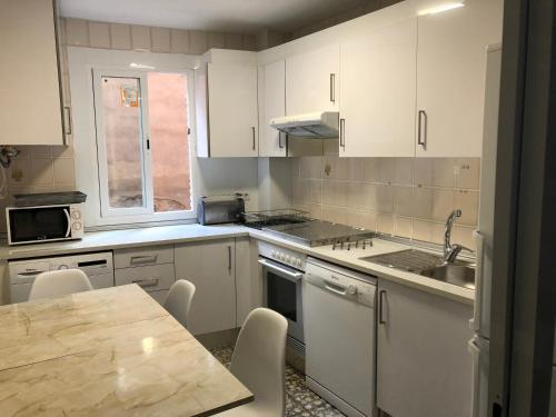 a kitchen with white cabinets and a table at Casa del Vado in Toledo