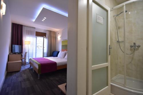 a hotel room with a bed and a shower at Hotel Hecco in Sarajevo