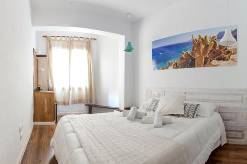 a white bedroom with a large white bed with pillows at Hostal Ibiza in Ibiza Town