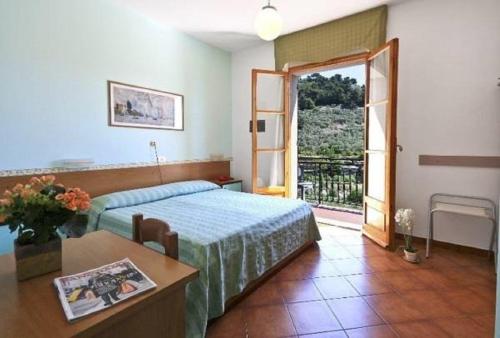 um quarto com uma cama, uma mesa e uma porta em Albergo Ristorante San Matteo em San Bartolomeo al Mare
