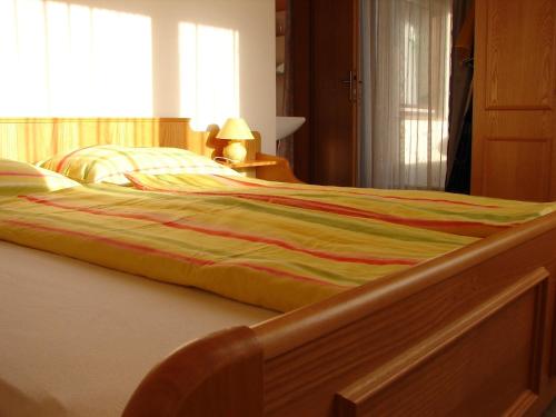 a large bed with a striped blanket on it at Ferienwohnungen Marktl in Sankt Kanzian