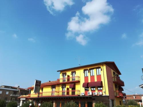a yellow and red building with a blue sky at Hotel Primavera in Peschiera del Garda