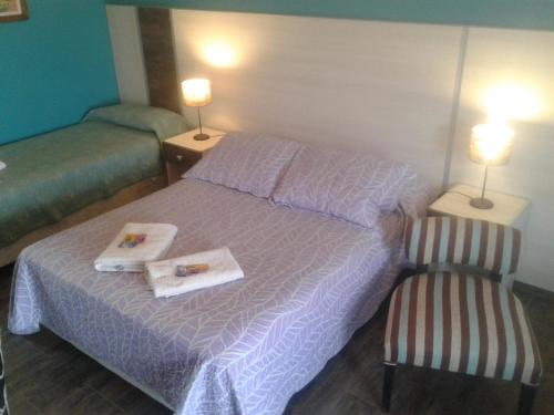 a bedroom with a bed with towels and a chair at Altos de Adonai in Pueblo Quintana