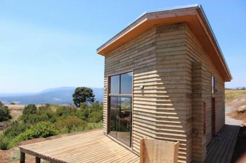 una pequeña casa de madera con terraza de madera en Reserva Los Maquis, en Cobquecura