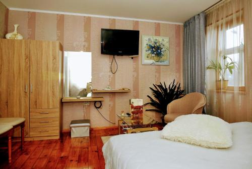 1 dormitorio con 1 cama y TV en la pared en Līvijas apartamenti, en Kuldīga