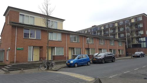 a small blue car parked in front of a brick building at Quiet spacious room in Amsterdam