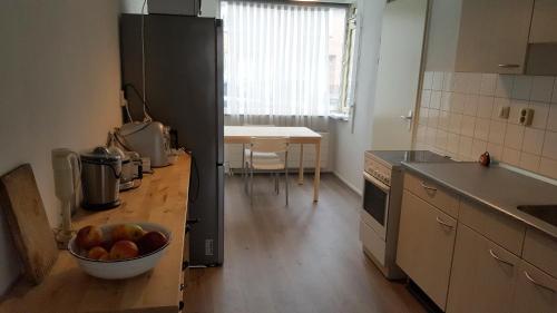 a kitchen with a table, a sink, and a refrigerator at Quiet spacious room in Amsterdam
