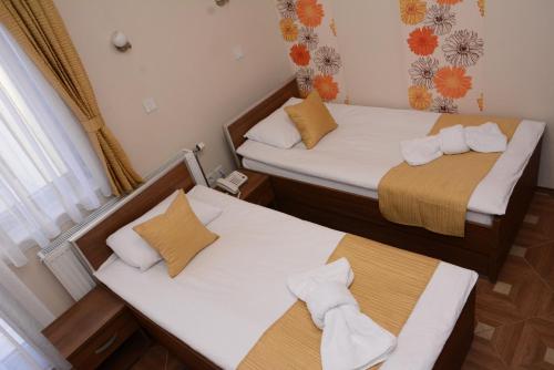 two beds in a small room with towels at Garni Hotel Laguna Lux in Niš