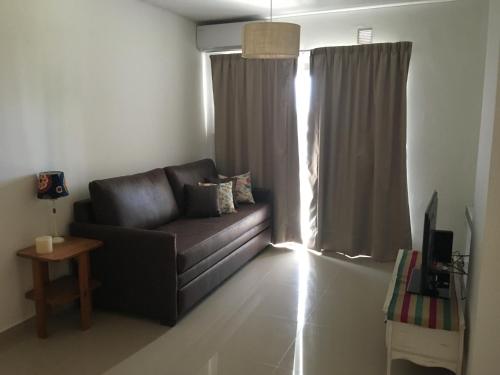 sala de estar con sofá de cuero y ventana en Hermoso departamento con piscina en Río Cuarto