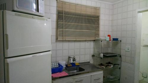 a small kitchen with a sink and a refrigerator at Apartamento Blue Sky in São Vicente