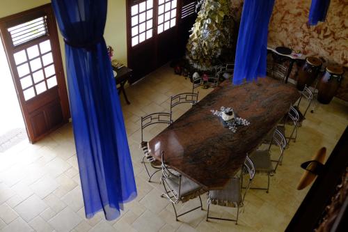 einen langen Holztisch in einem Zimmer mit blauen Vorhängen in der Unterkunft Bed and breakfast Riviere in Le Marin