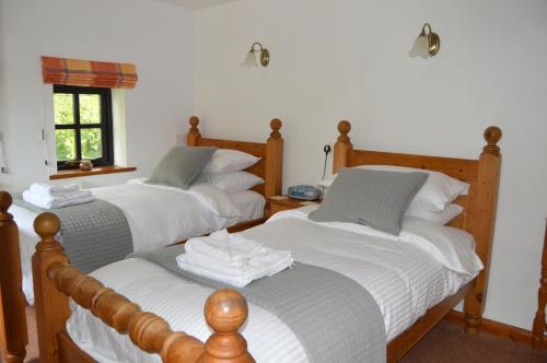 a bedroom with three beds with white sheets and a window at Shipload Cottage in Hartland