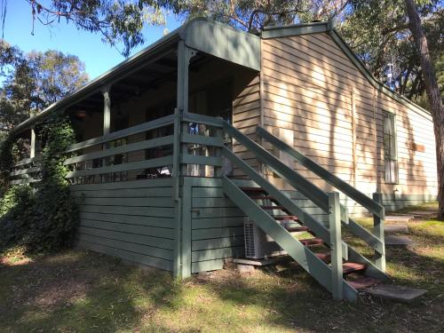a wooden cabin with a staircase leading to it at Day Dream Cottage in Halls Gap