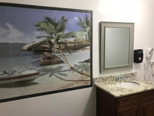 uma casa de banho com uma fotografia de uma praia e um lavatório em norwalk inn & suites em Norwalk