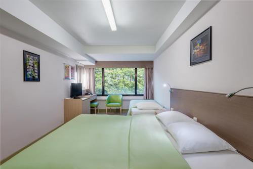 a hotel room with two beds and a desk at YHA Mei Ho House Youth Hostel in Hong Kong