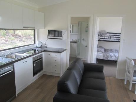 een woonkamer met een bank en een keuken bij Just Red Wines Cabins in Ballandean