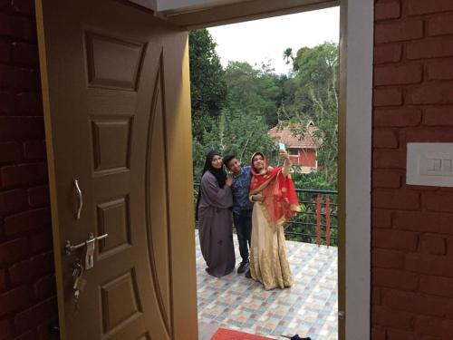 a group of three women standing outside a door at Marsim Holiday Resort in Vythiri