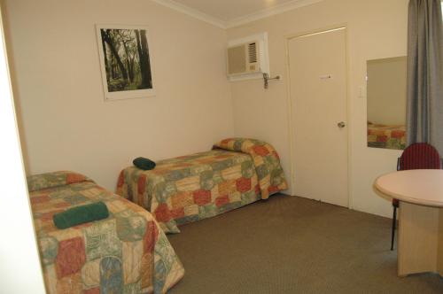 a small room with two beds and a table at Collie Forest Motel in Collie
