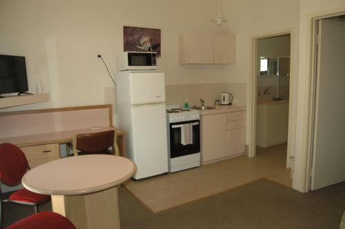 a small kitchen with a white refrigerator and a table at Collie Forest Motel in Collie