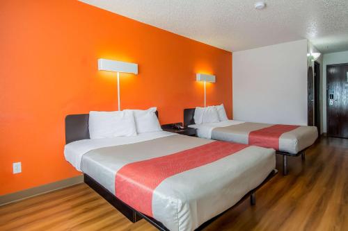 two beds in a room with an orange wall at Motel 6-Dallas, TX - North - Richardson in Dallas