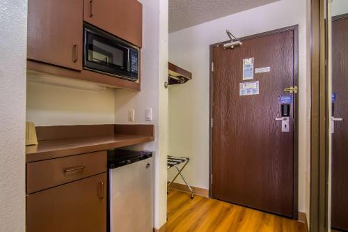 a small kitchen with a door and a microwave at Motel 6-Dallas, TX - North - Richardson in Dallas