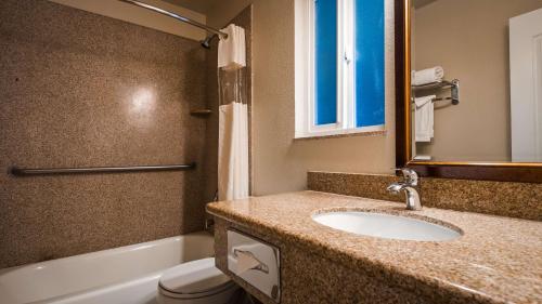 a bathroom with a sink and a toilet and a mirror at Best Western Tradewinds in Morro Bay