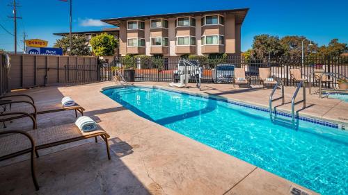 a swimming pool with chairs next to a building at Best Western De Anza Inn in Monterey
