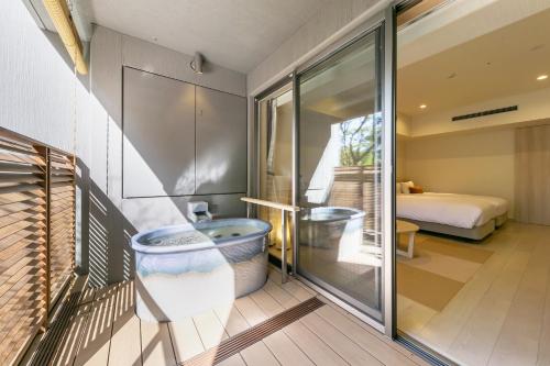a bathroom with a tub and a bedroom at Hakone Ashinoko Hanaori in Hakone