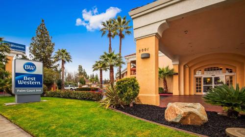 a best western sign in front of a building at Best Western Palm Court Inn in Modesto