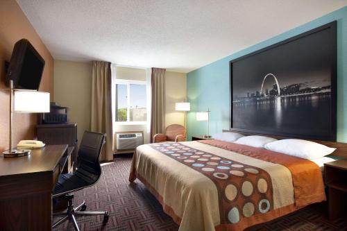 a hotel room with a bed and a desk and a large screen at Super 8 by Wyndham Fairview Heights-St. Louis in Fairview Heights