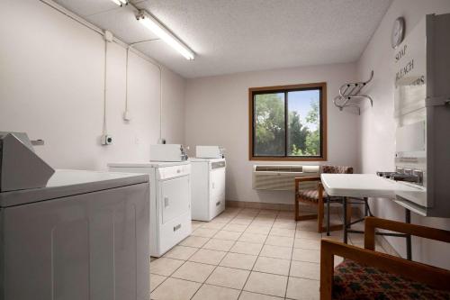 a kitchen with white cabinets and a table and a window at Super 8 by Wyndham Westminster Denver North in Westminster