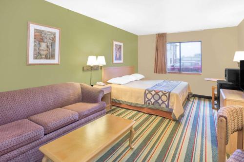 a hotel room with a bed and a couch at Super 8 by Wyndham East Moline in East Moline