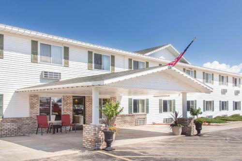 a white building with red chairs in front of it at Super 8 by Wyndham Escanaba in Escanaba