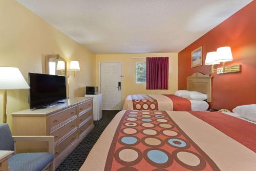 a hotel room with two beds and a flat screen tv at Super 8 by Wyndham Chipley in Chipley