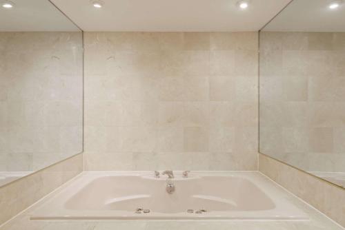 een badkamer met een bad en een grote spiegel bij Super 8 by Wyndham Sturbridge in Sturbridge