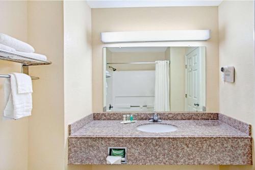 a bathroom with a sink and a mirror at Super 8 by Wyndham Forrest City AR in Forrest City