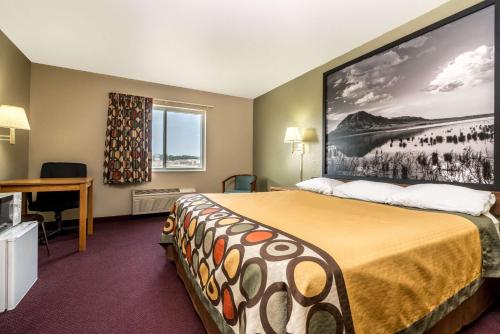 a hotel room with a bed with a large picture on the wall at Super 8 by Wyndham Beresford in Beresford