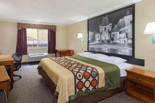 a hotel room with a bed with a large picture on the wall at Super 8 by Wyndham Los Angeles Downtown in Los Angeles
