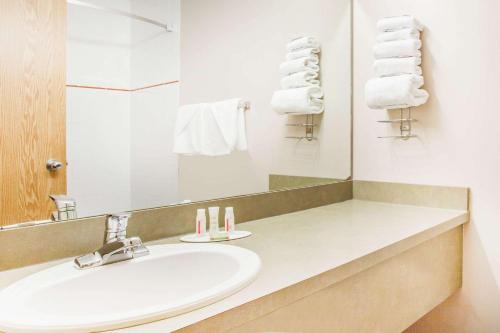 y baño con lavabo, espejo y toallas. en Super 8 by Wyndham Meadow Lake, en Meadow Lake