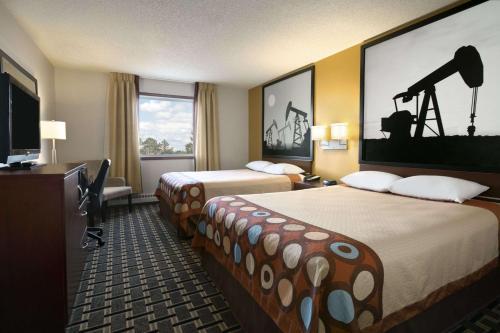 a hotel room with two beds and a television at Super 8 by Wyndham Fox Creek in Fox Creek