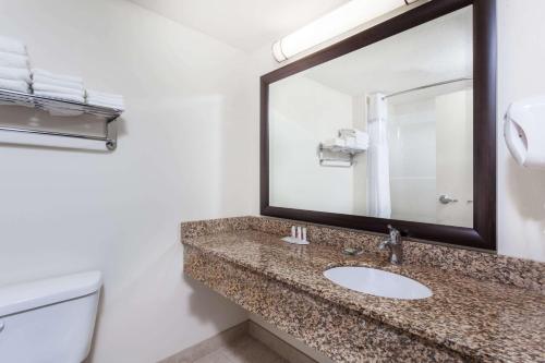 a bathroom with a sink and a mirror and a toilet at Super 8 by Wyndham Sherwood Park/Edmonton Area in Sherwood Park
