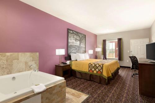 - une chambre d'hôtel avec un lit et une baignoire dans l'établissement Super 8 by Wyndham Carrizo Springs, à Carrizo Springs