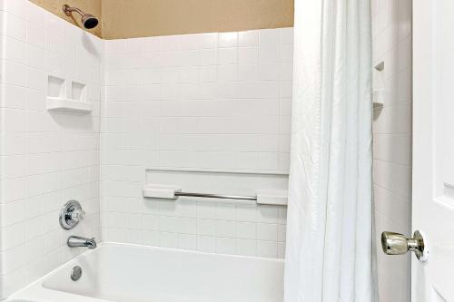 un bagno bianco con vasca e tenda per la doccia di Super 8 by Wyndham Jackson Ridgeland a Jackson