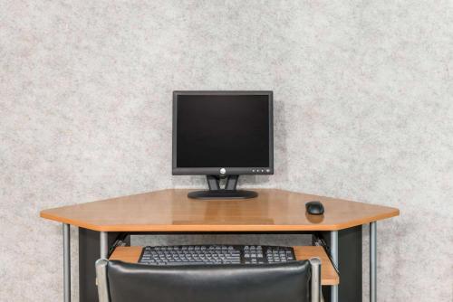 a desk with a computer monitor and a keyboard and mouse at Super 8 by Wyndham Hancock MD in Hancock