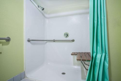 a bathroom with a shower with a blue shower curtain at Super 8 by Wyndham Osseo WI in Osseo